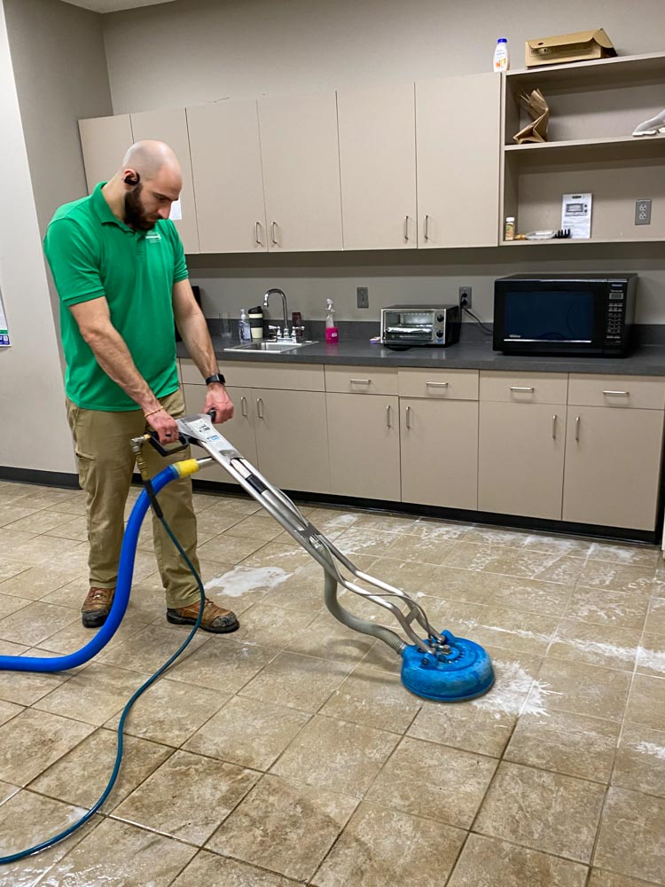 Technician deep-cleaning tile and grout with a rotary extraction tool