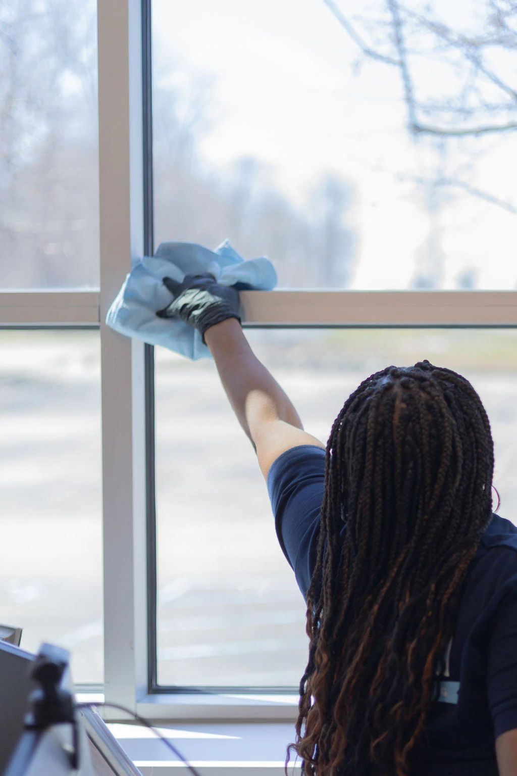 Technician cleaning interior window glass in a commercial office