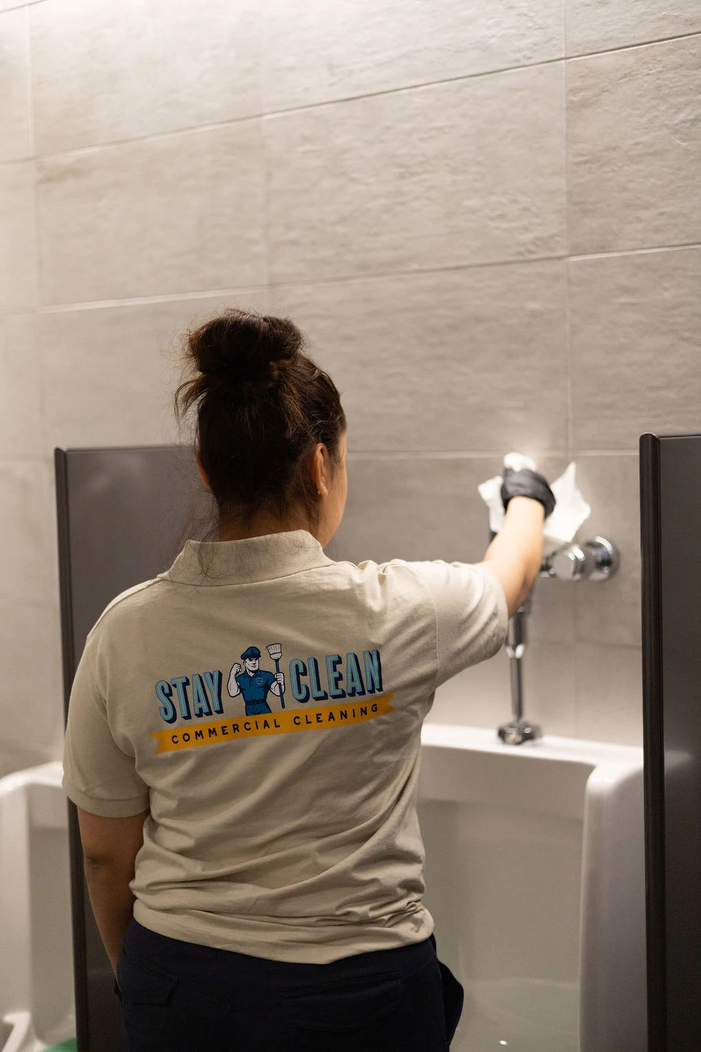 A uniformed Stay Clean technician servicing a commercial restroom