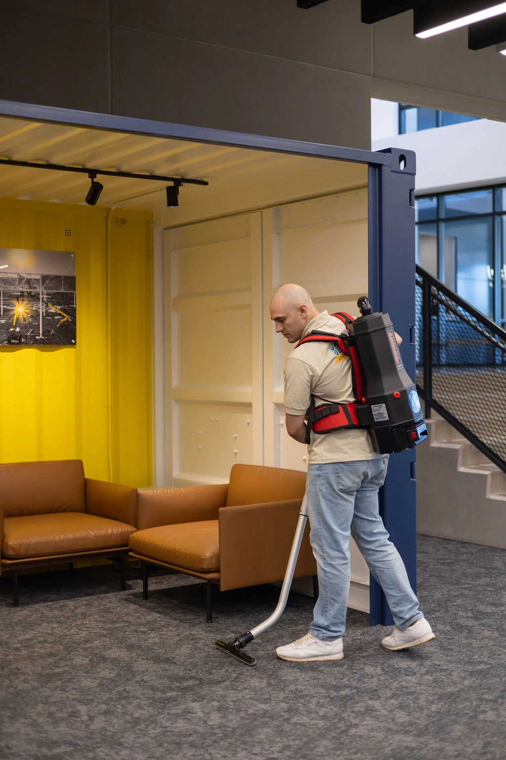 Technician vacuuming commercial carpet with a backpack vacuum